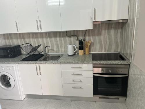 een keuken met witte kasten, een wastafel en een vaatwasser bij Apartamento Sunny in Albufeira