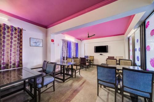 a dining room with tables and chairs and a tv at Hotel O JNTU college Near LULU mall, KPHB Colony. in Hyderabad