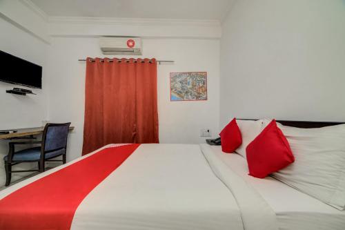 Cette chambre comprend un lit avec des oreillers rouges et un bureau. dans l'établissement Super OYO JNTU college Near LULU mall, KPHB Colony., à Kukatpally