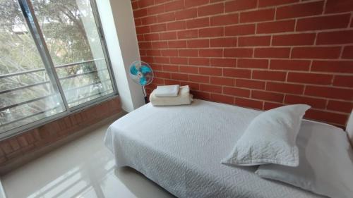 a bedroom with a brick wall and a bed with pillows at ApartaHotel Montes Medellin in Medellín