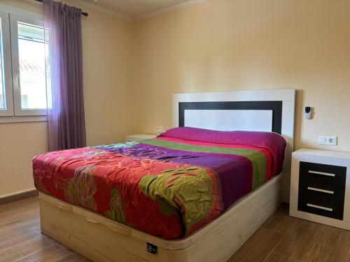 1 dormitorio con 1 cama grande y edredón colorido en Casa a dos minutos caminando del mar en Denia
