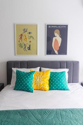 a bed with green and yellow pillows on it at Studio KG in Kragujevac