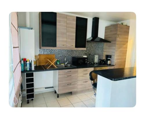 una cucina con armadi in legno e piano di lavoro nero di Chambre spacieuse et lumineuse a Nanterre