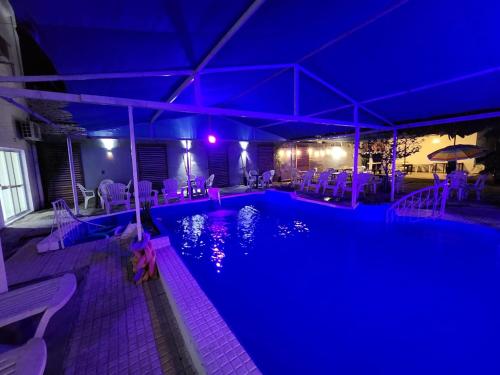 a swimming pool lit up at night with purple lights at Hotel Australia in Termas de Río Hondo