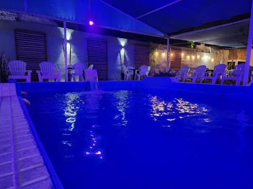 una piscina notturna con sedie e tavoli bianchi di Hotel Australia a Termas de Río Hondo