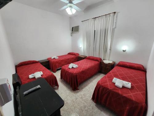 3 Betten in einem Zimmer mit roter Bettwäsche in der Unterkunft Hotel Australia in Termas de Río Hondo