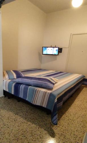a bedroom with a bed with a tv on the wall at Downtown São Lourenço: Comfort and Convenience in São Lourenço