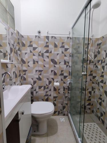 a bathroom with a toilet and a glass shower at Downtown São Lourenço: Comfort and Convenience in São Lourenço