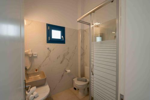 a bathroom with a toilet and a glass shower at HELIADES SUITES in Panteli