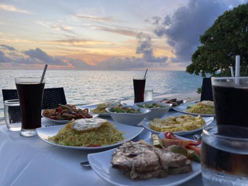 una mesa con platos de comida y bebida en la playa en Thoddoo Island Holiday Inn en Thoddoo