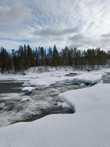 a river covered in snow with trees in the background at Nordic character in Vidsel