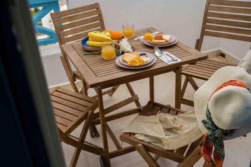 a wooden table with a plate of fruit and glasses of orange juice at HELIADES SUITES in Panteli
