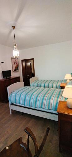 a bedroom with a bed with striped sheets and a desk at Villa Mazzini in Molinella