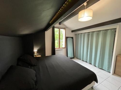 sypialnia z czarnym łóżkiem i oknem w obiekcie Charmante maison mitoyenne w mieście Melun