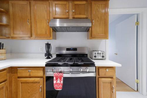 a stove top oven in a kitchen with wooden cabinets at Convenient Braintree Home - 3 Bedroom Sleeps 8 in Braintree