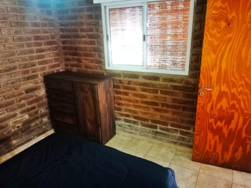 a bedroom with a brick wall and a bed and a window at Complejo Hatun Yaya in Mendoza