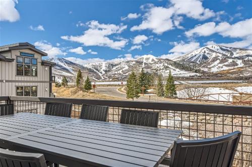 a table and chairs on a balcony with snow covered mountains at Helling Circle Hideaway 303 condo in Heber City