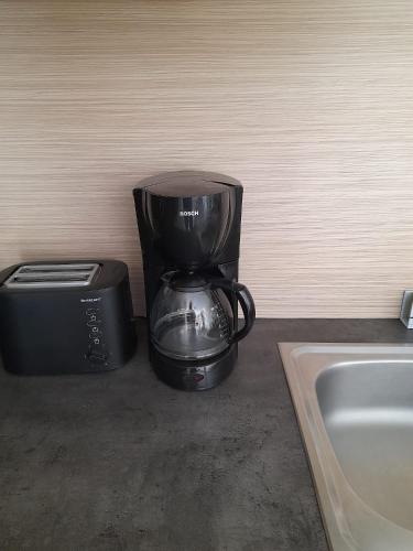 une cafetière et un grille-pain à côté d'un évier dans l'établissement Appart T3 Terrasse - Piscine - 3 étoiles, à Saint-Cyprien