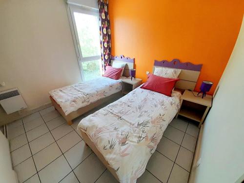 um quarto com 2 camas e uma parede laranja em Appart T3 Terrasse - Piscine - 3 étoiles em Saint-Cyprien