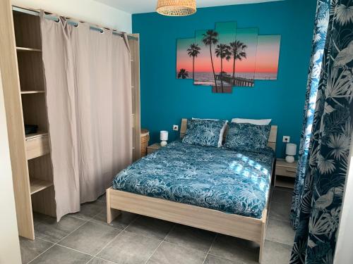 1 dormitorio con cama y pared azul en Maison T2 situé à Sainte Anne, en Sainte-Anne