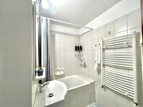 a white bathroom with a sink and a bath tub at Valcea Northside Spacious Apartment in Râmnicu Vâlcea