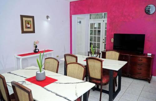 a dining room with pink walls and tables and chairs at Hotel Boutique Rosse in San Pedro Sula