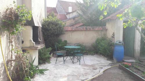a patio with a table and chairs in a courtyard at Chambre agréable au fond du jardin in Sancoins