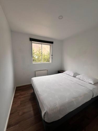 - une chambre avec un grand lit blanc et une fenêtre dans l'établissement hostal el glaciar, à Refugio Lo Valdés