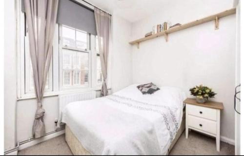 a white bedroom with a bed and a window at Bridgestone in London