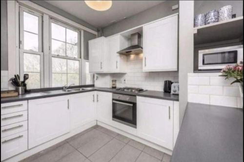 a kitchen with white cabinets and a stove top oven at Bridgestone in London