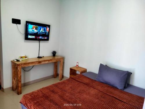 a bedroom with a bed and a tv on the wall at WiHouse Bali in Denpasar