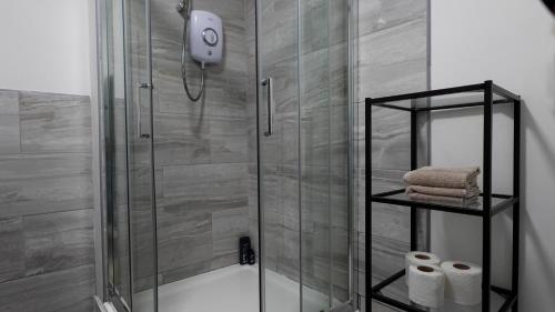 - une douche avec une porte en verre et quelques serviettes dans l'établissement The StayLuxe Apartment Manchester, à Manchester