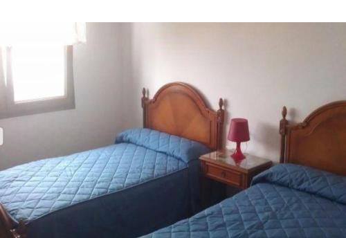 een slaapkamer met 2 bedden en een tafel met een lamp bij Piso con vistas al puerto in Lastres