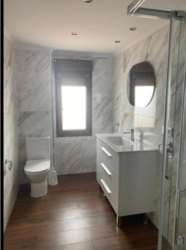 een badkamer met een toilet, een wastafel en een spiegel bij Piso con vistas al puerto in Lastres