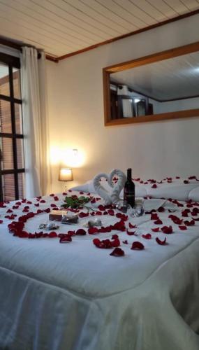 a bed covered in red rose petals and two swans at Pousada Atalaia Capivari in Campos do Jordão