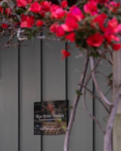 a bunch of red flowers with a sign on a fence at Bow Street Apartments & Cottage in Raglan