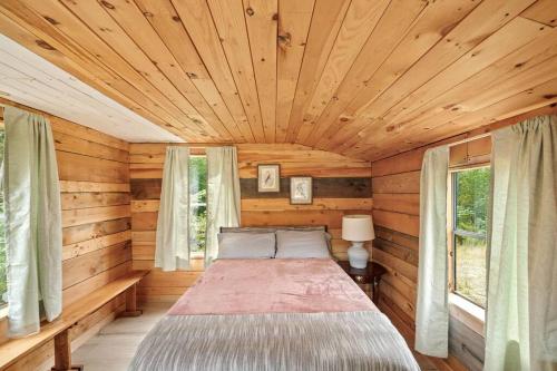 1 dormitorio con 1 cama en una cabaña de madera en Cute Cabin in the Woods, en Surry