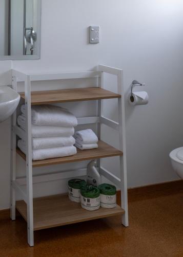 a bathroom with a shelf with towels and a sink at Bow Street Apartments & Cottage in Raglan