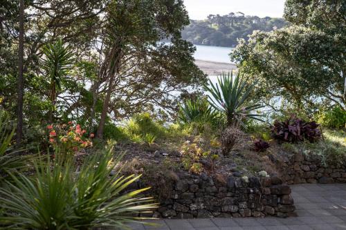 a garden with a stone wall and plants at Bow Street Apartments & Cottage in Raglan