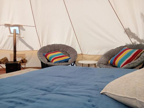 モンテベルデ・コスタリカにあるBetter Life Mountain Camp Monte Verdeのテント内のベッド1台と椅子2脚
