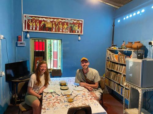 Un uomo e una donna seduti a un tavolo in una stanza blu di Catch The Ella Train Hostel a Kandy