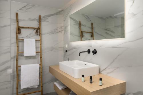 a white bathroom with a sink and a mirror at Loulou House in Agia Kiriaki Beach
