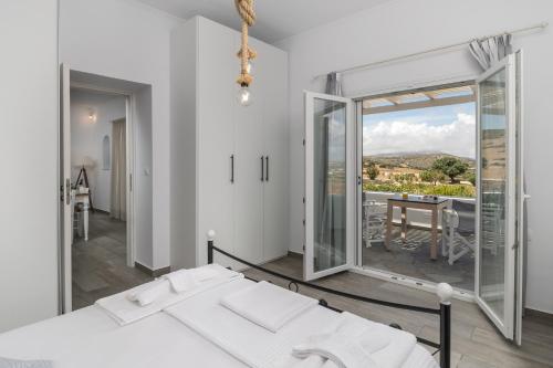 a bedroom with a bed and a table and a balcony at Loulou House in Agia Kiriaki Beach
