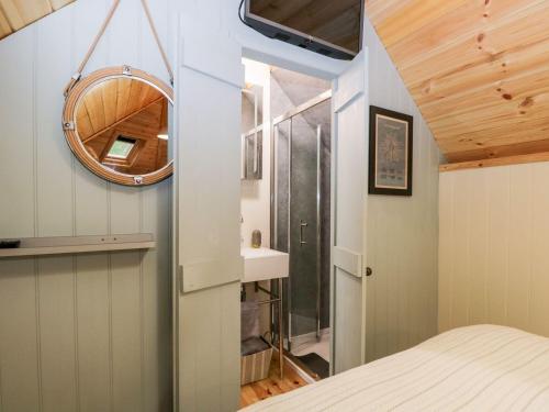 ein kleines Schlafzimmer mit einem Bett und einem Spiegel in der Unterkunft Woodmans Huts in Haverthwaite