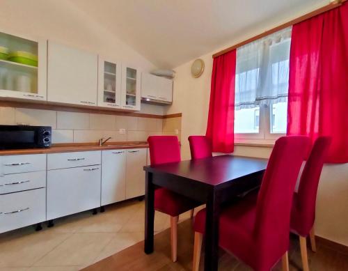 a kitchen with a dining room table and red chairs at Apartments Zova in Medulin