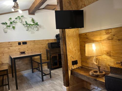 a room with a wooden wall with a table and a television at Two-Bedroom Cosy Country Lodge with Private Patio in Greenhithe