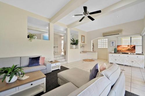 a living room with a couch and a ceiling fan at Sandy Cove @ Royle Palms in Bargara