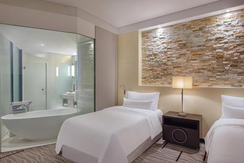 um quarto de hotel com uma cama e uma banheira e uma cama e uma cama em The Westin City Centre Bahrain em Manama