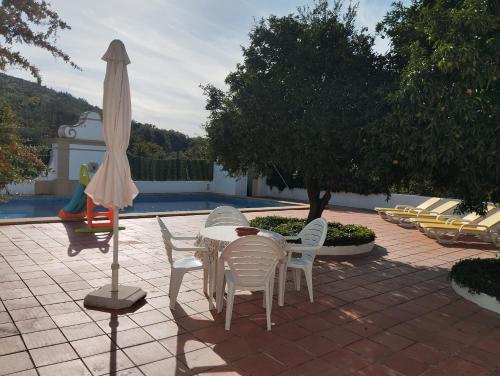 a patio with a table and chairs and an umbrella at Casa Do Ginjal by NaturAlegre in Marvão