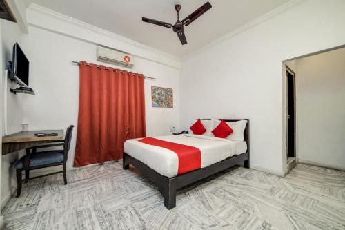 a bedroom with a bed with a red curtain and a desk at Hotel O JNTU college Near LULU mall, KPHB Colony. in Hyderabad